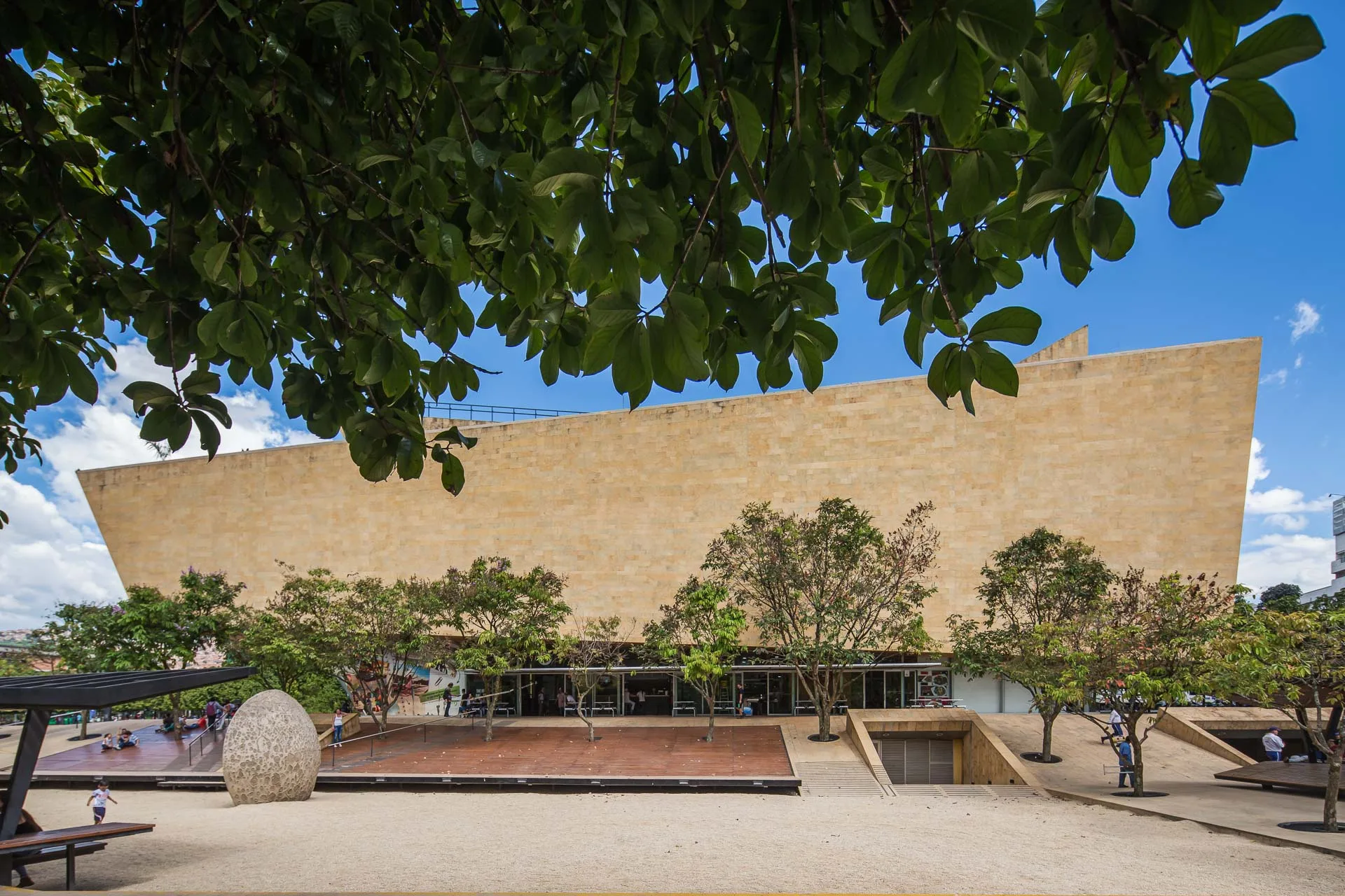 Plaza urbana del Parque de los Deseos en Medellín por +udeb. Espacio público con arena, agua y la pantalla de cine al aire libre.
